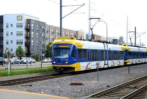 Light rail train beside new transit-oriented housing